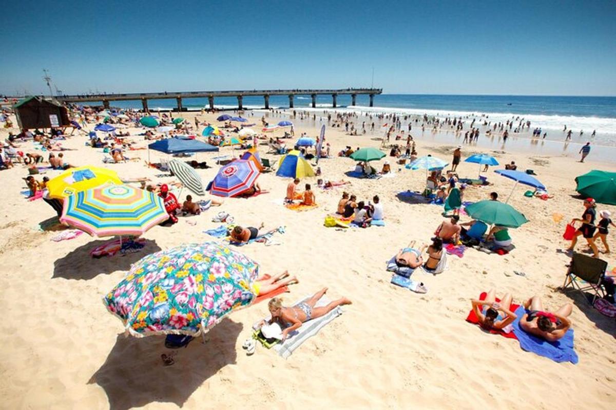 a crowd of people on a beach with umbrellas