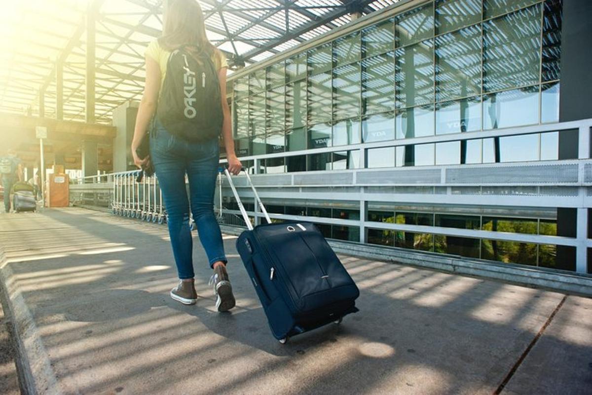 naine kõnnib mööda kõnniteed kohvrit vedades