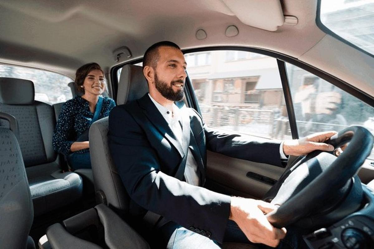 vyras su kostiumu vairuoja automobilį su moterimi