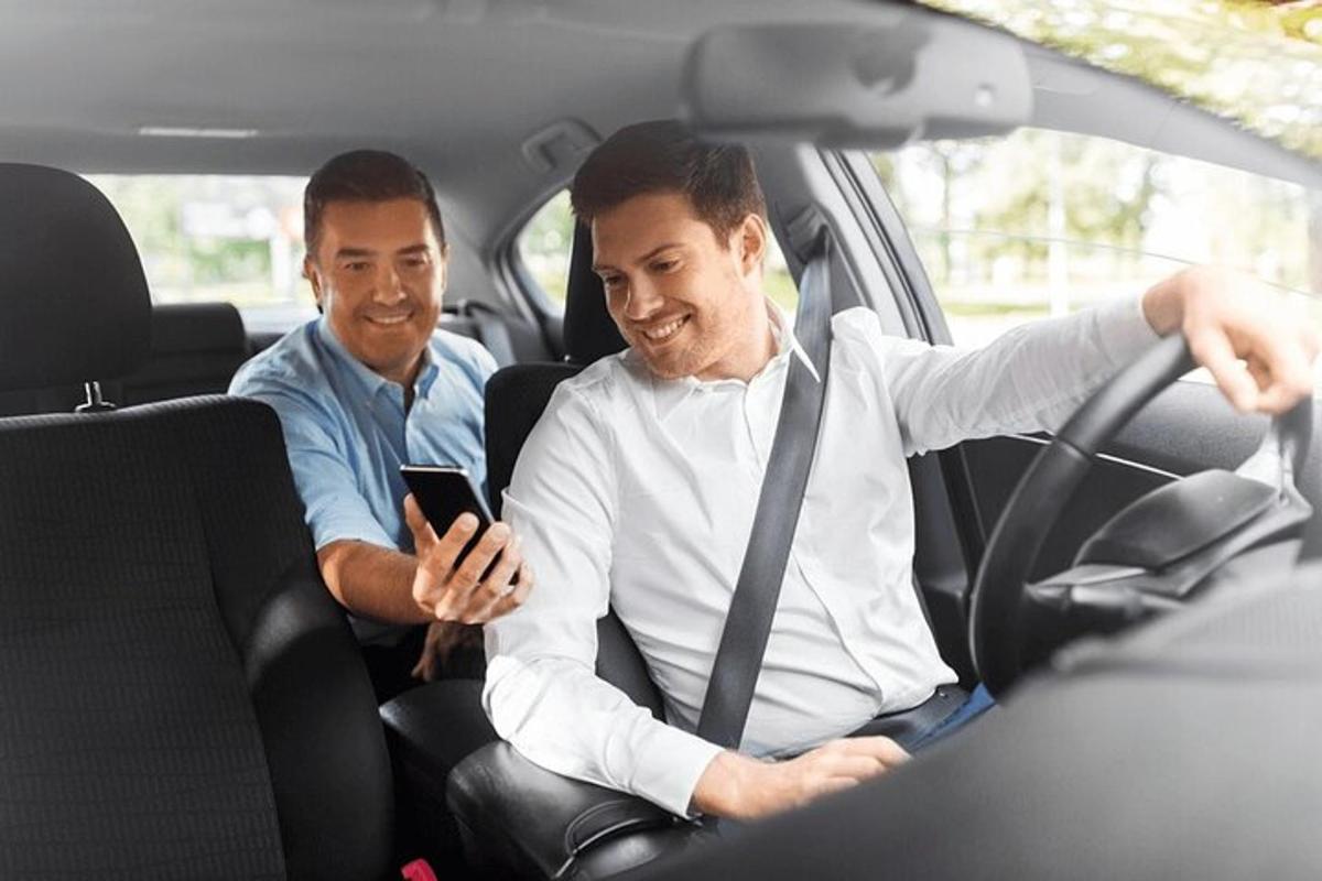 two men sitting in a car looking at a cell phone