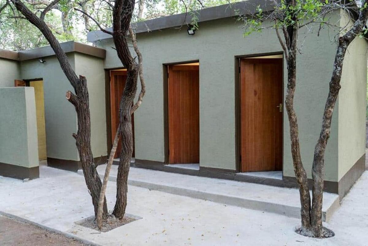 Un edificio con tres puertas y tres árboles al frente.
