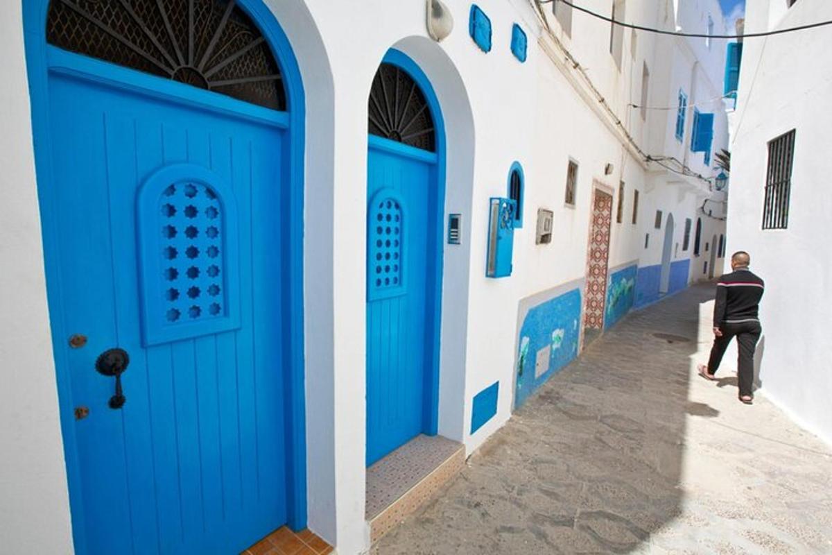 a man walking down a street with blue doors