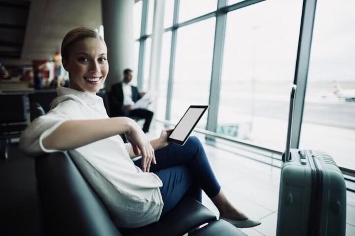 uma mulher sentada em um aeroporto com um tablet