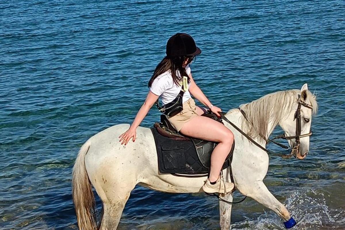 una giovane ragazza che cavalca un cavallo bianco nell'acqua