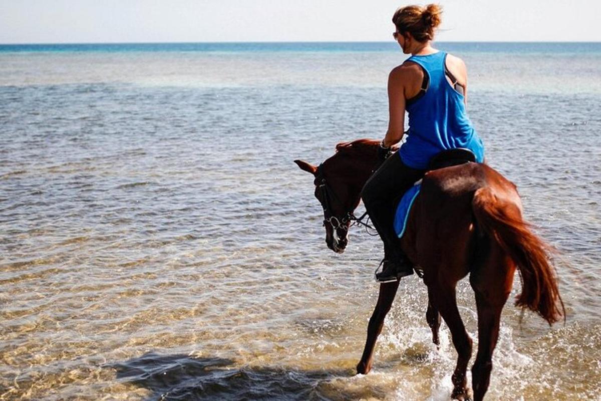 en kvinne som rir på en hest på stranden