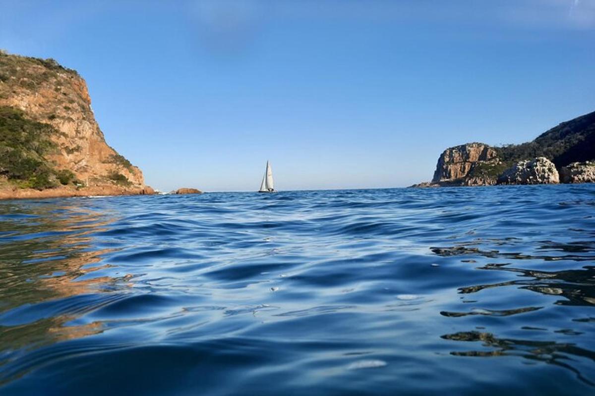 a sailboat in the water near a rocky coast
