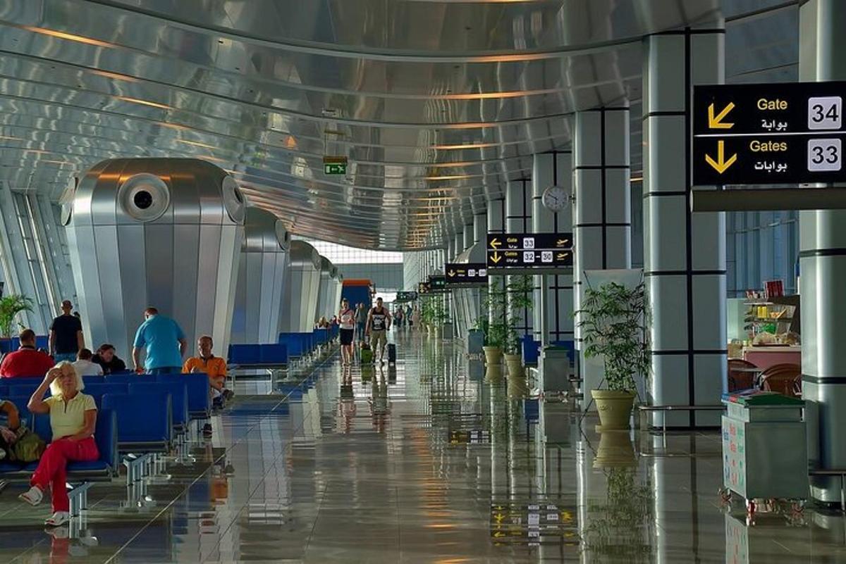 Un pasillo del aeropuerto con gente sentada en mesas en la terminal.