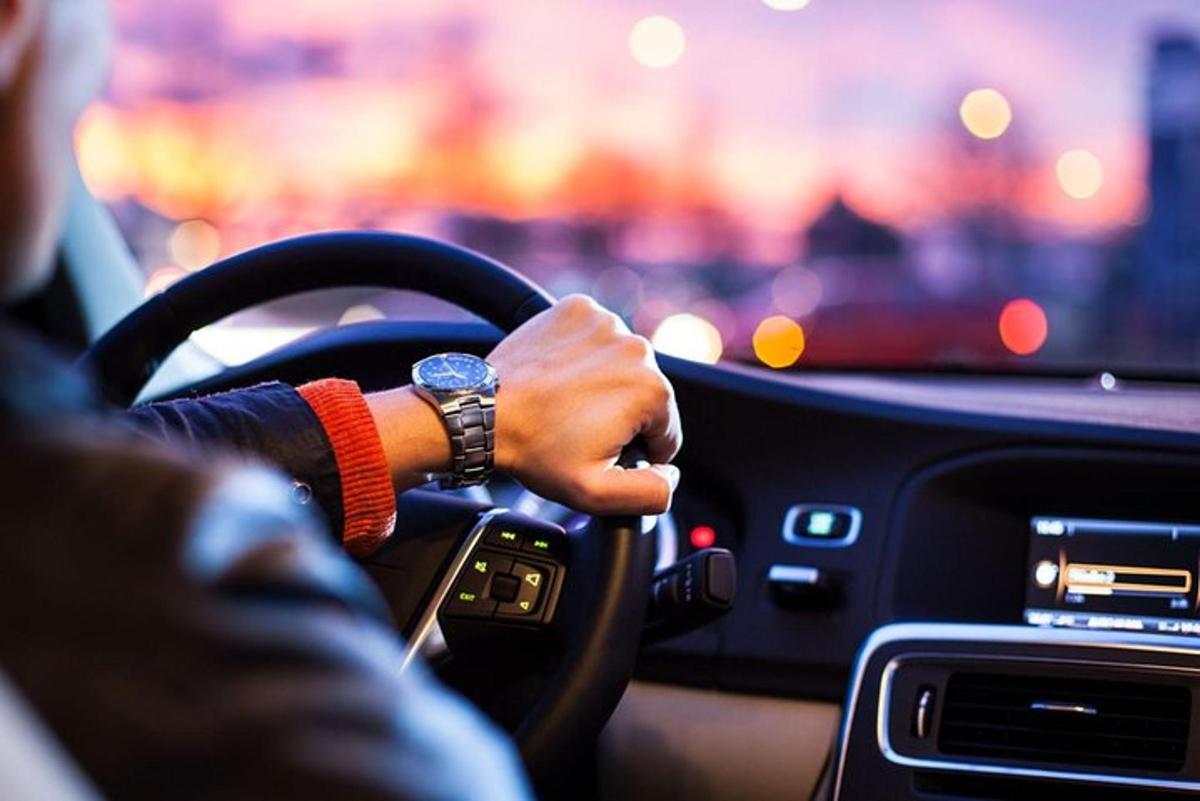 一名男子驾驶汽车，手放在方向盘上