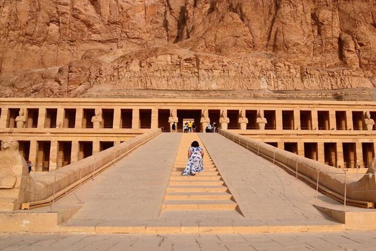 a woman in a dress sitting on steps in front of a mountain