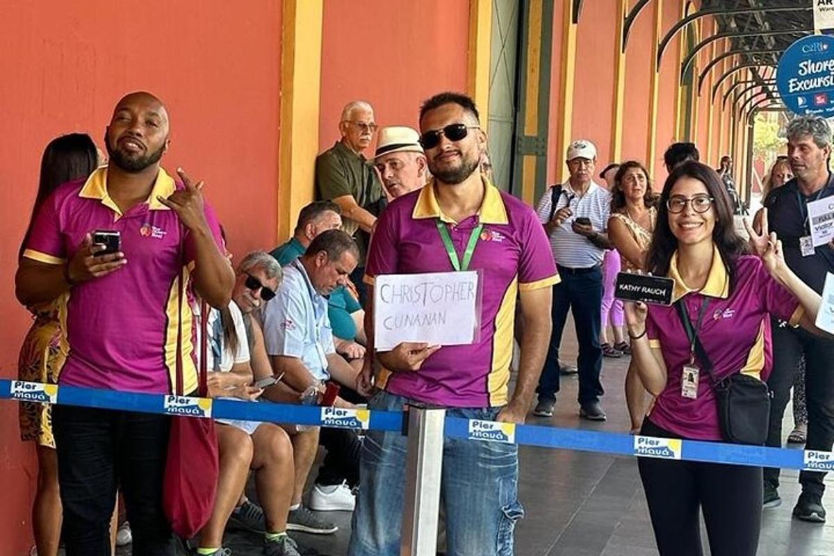 grupa ljudi u ljubičastim majicama stoji iza vrpce