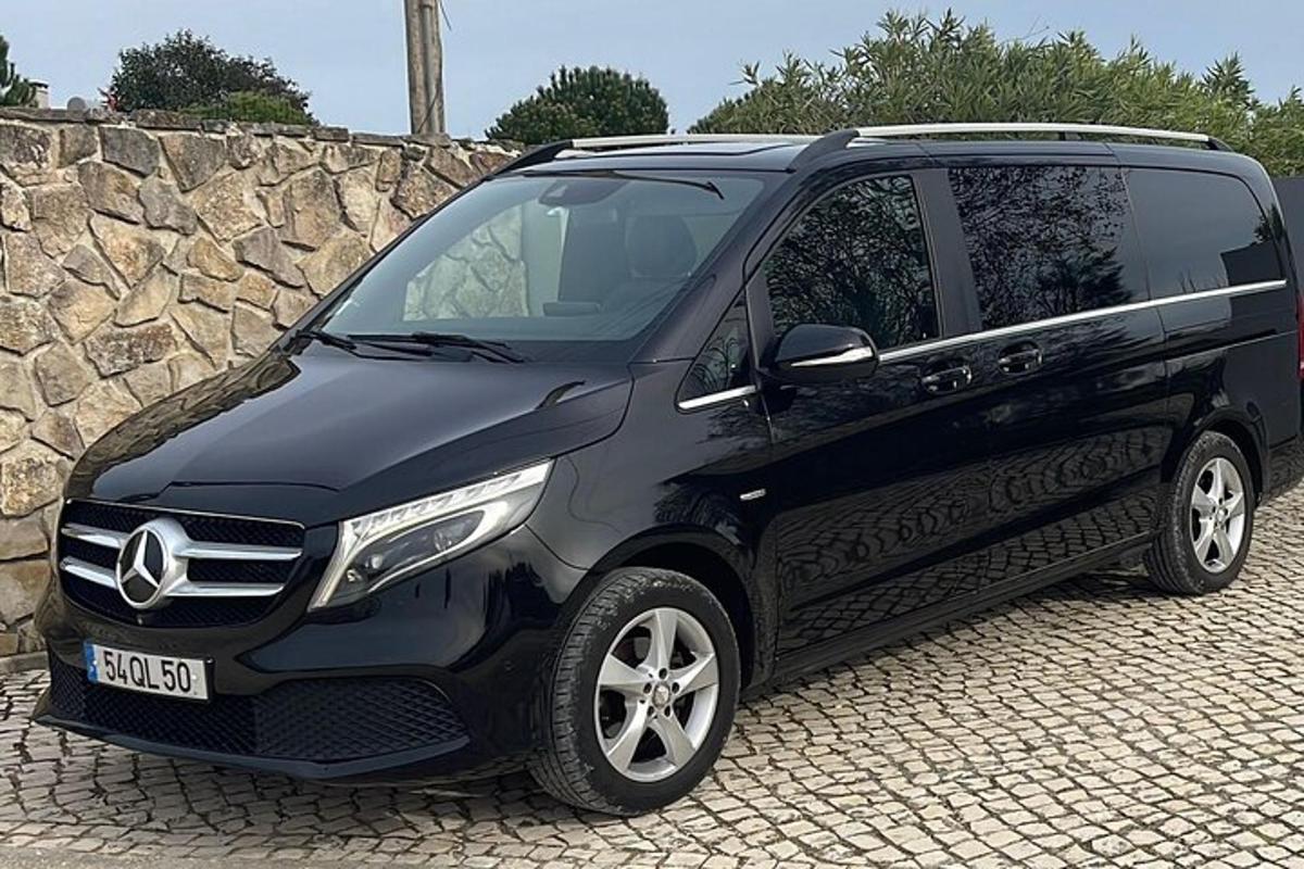 melns apvidus auto, kas novietots blakus akmens sienai