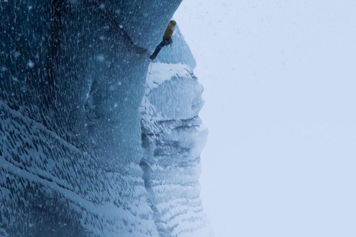 una persona in piedi sulla cima di una montagna coperta di neve