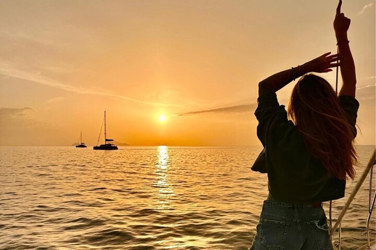 en kvinde stående på en båd i havet ved solnedgang