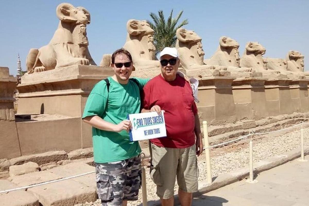 zwei Männer halten ein Schild vor einem Denkmal