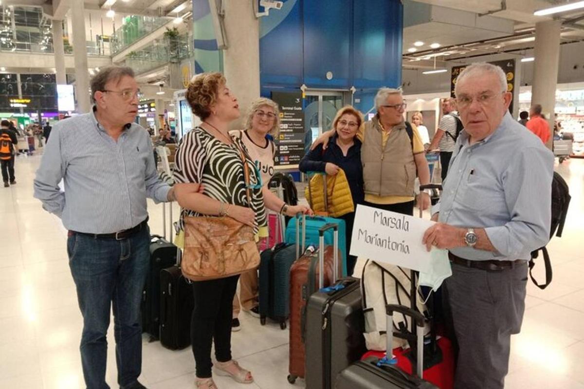 un grup de persones dempeus en un aeroport amb equipatge