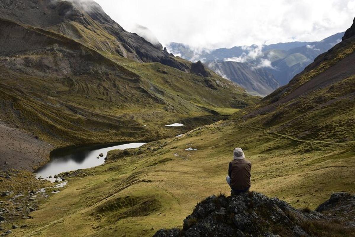eine Person, die auf einem Felsen sitzt und auf einen Berg blickt