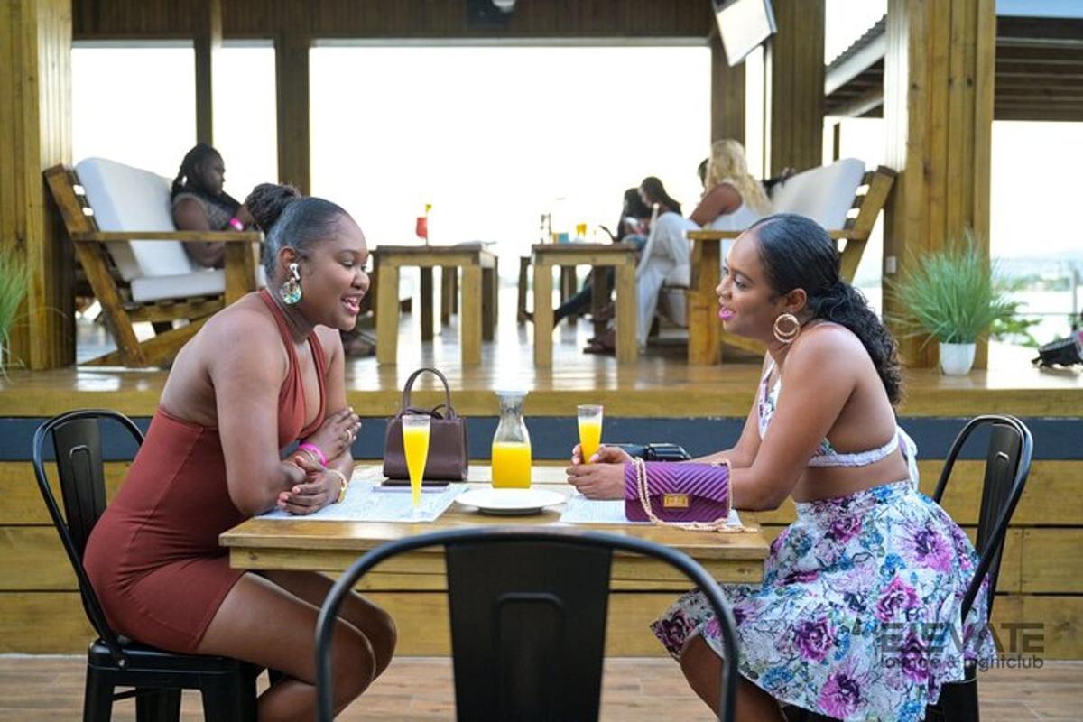 duas mulheres sentadas à mesa com bebidas