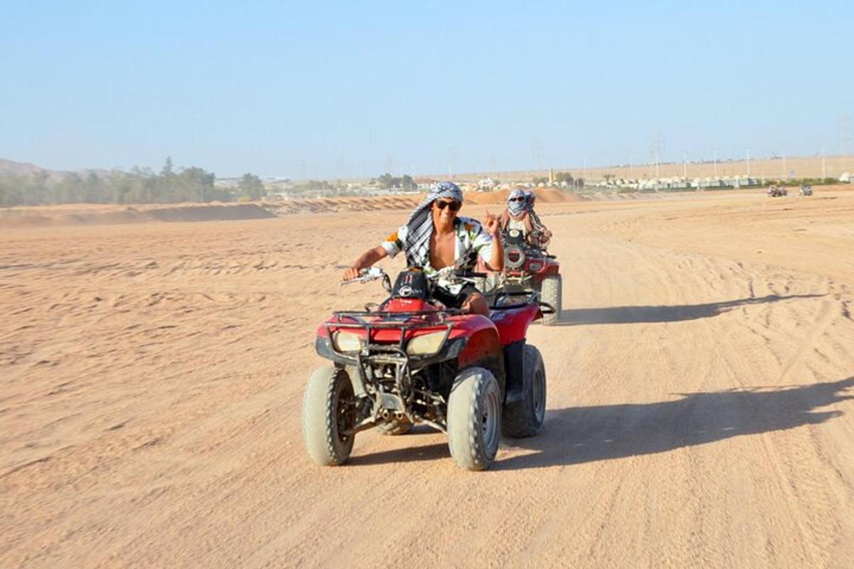 two people riding on four wheelers on the desert