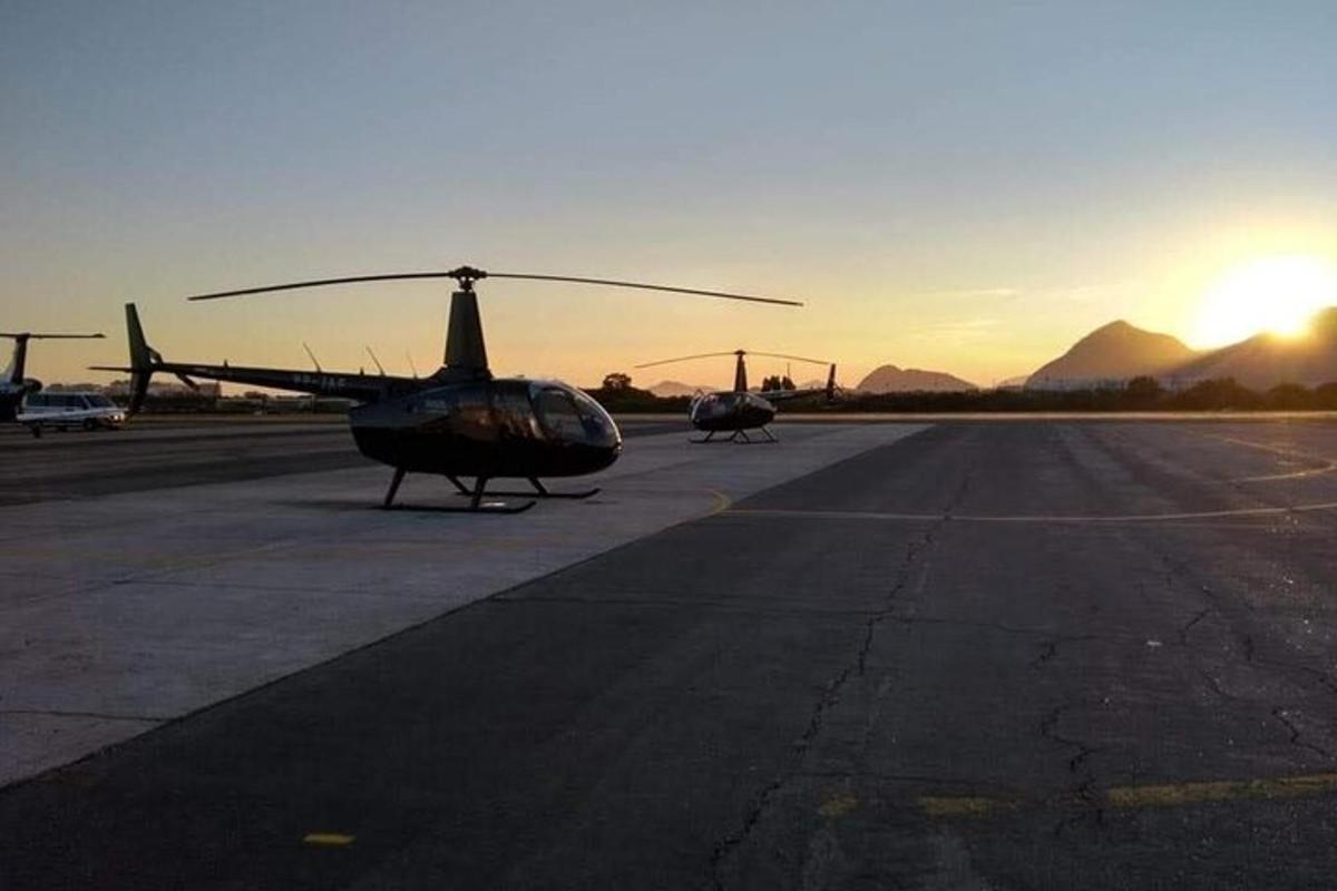 Dos helicópteros están estacionados en una pista al atardecer