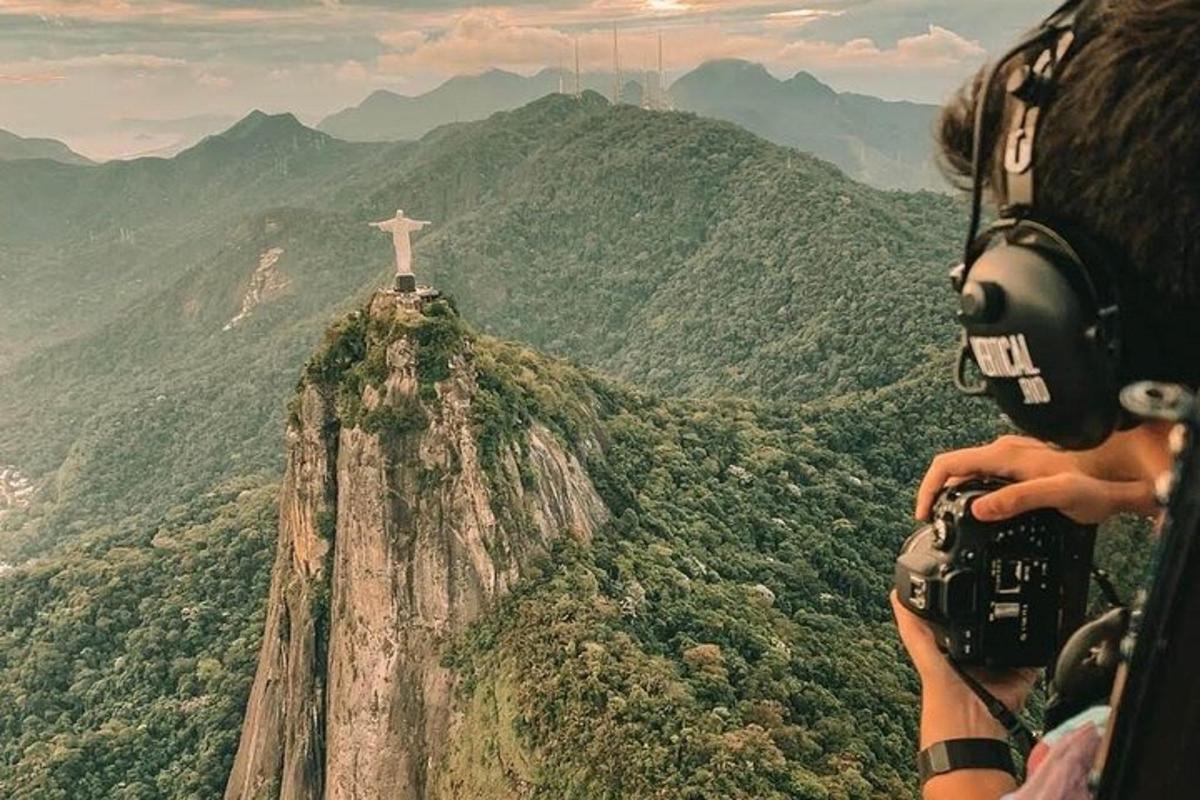 Una persona tomando una fotografía del Cristo Redentor en una montaña.