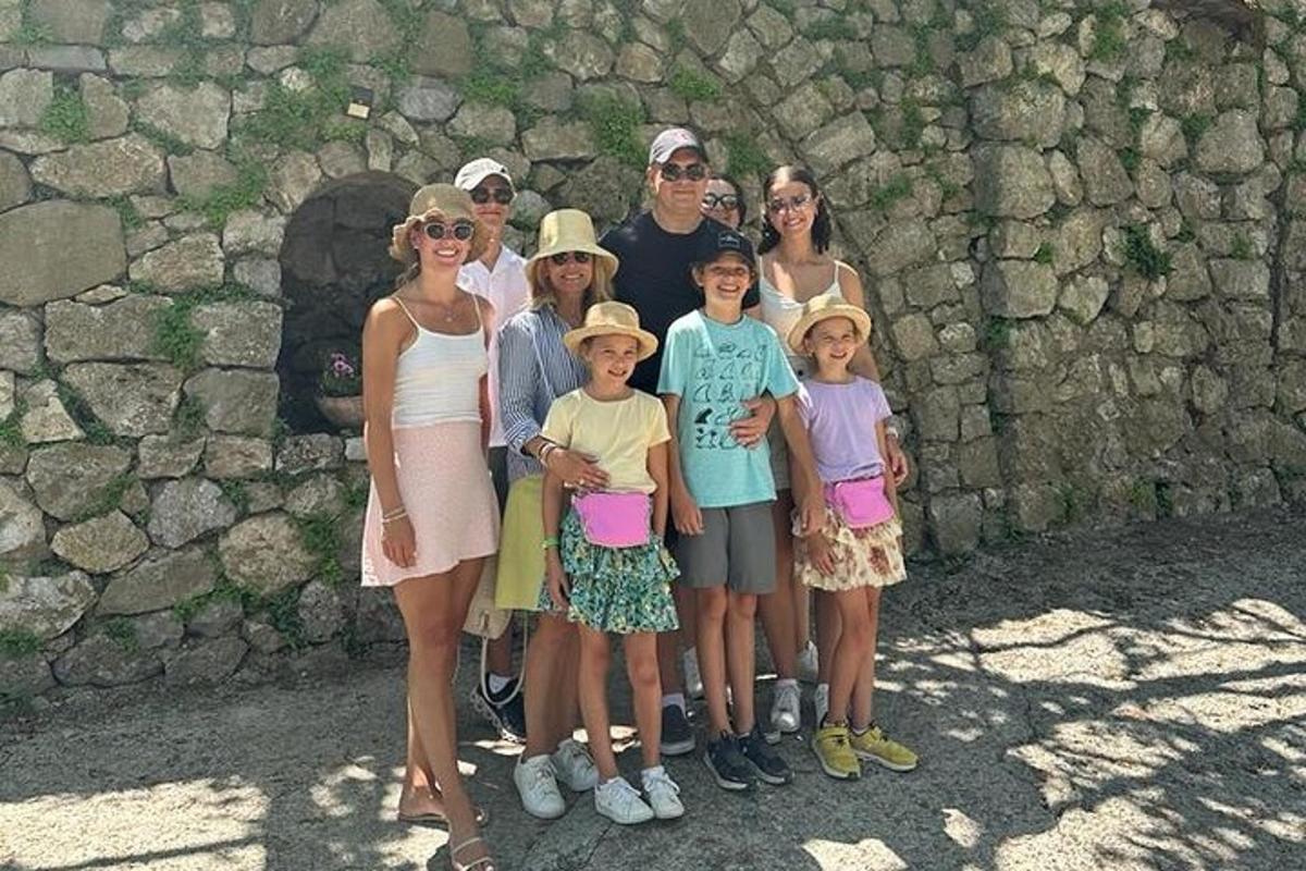 Una familia posando para una foto frente a un muro de piedra.