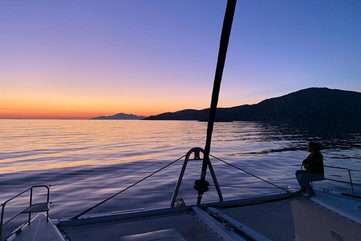 ένα άτομο που κάθεται στην πλώρη ενός σκάφους στο ηλιοβασίλεμα