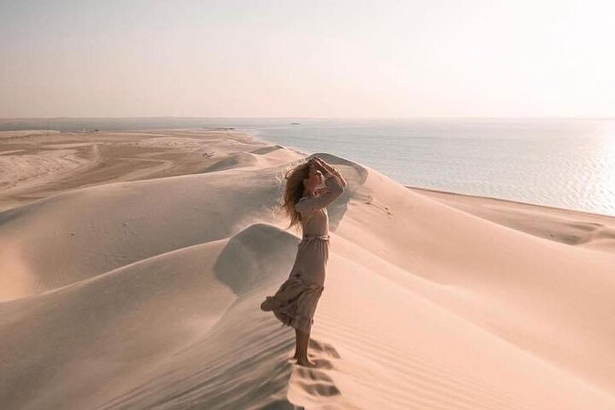 a woman standing on a sand dune in the desert