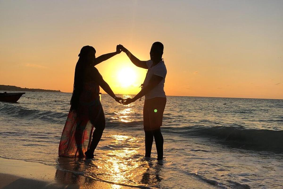 duas pessoas de mãos dadas na praia ao pôr do sol