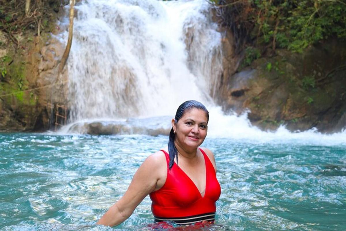 una donna in piedi nell'acqua di fronte a una cascata