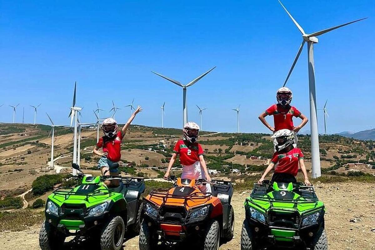 un gruppo di persone in sella a quad davanti alle turbine eoliche