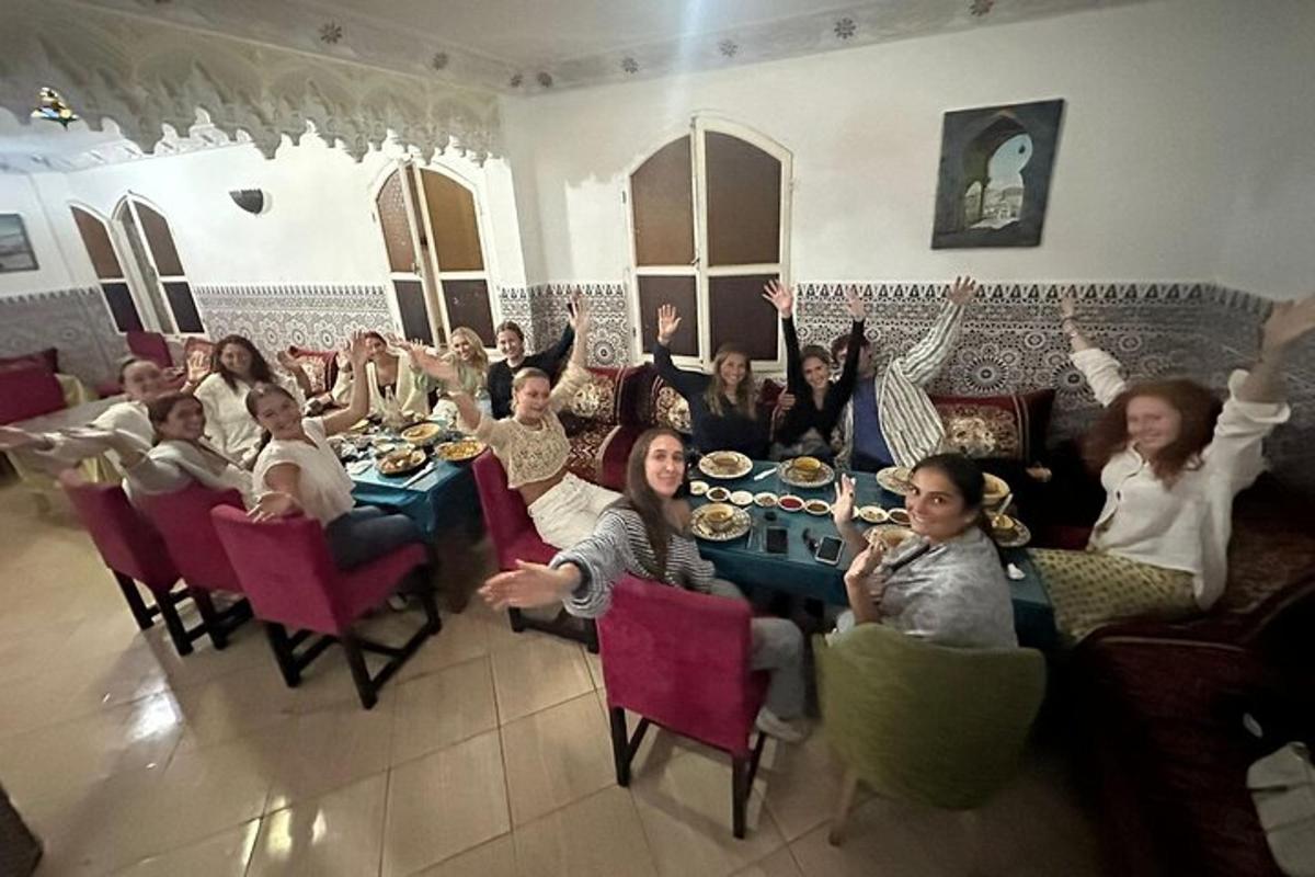 hópur fólks situr við borð með hendurnar í loftinu