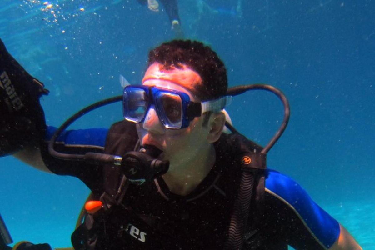 Un hombre con gafas de sol está bajo el agua con un micrófono.