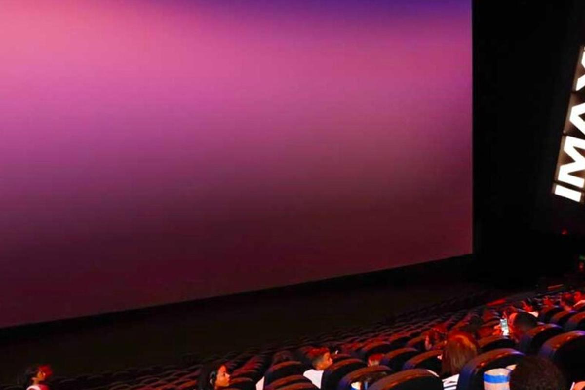 un pubblico in un auditorium che guarda uno schermo viola