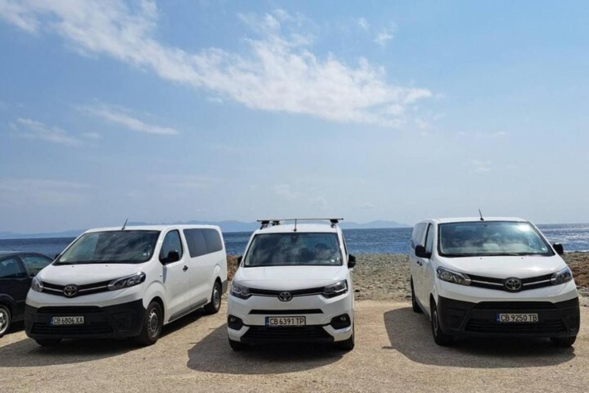 two white vans parked on a beach near the ocean