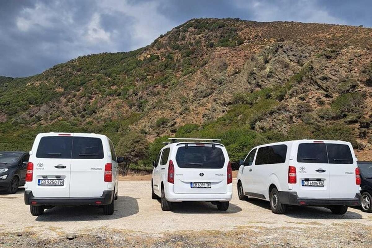 tiga mobil van putih terparkir di tempat parkir di depan gunung