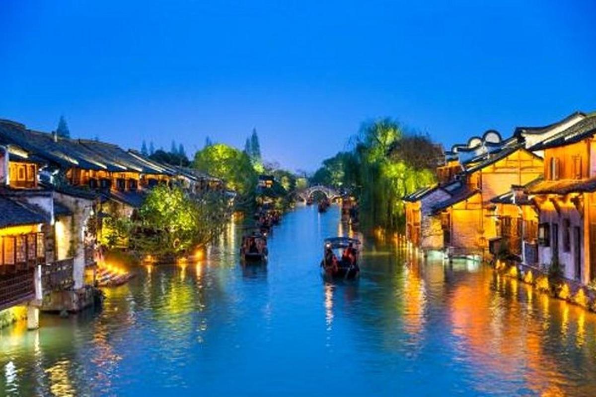 a river with buildings and boats on it at night