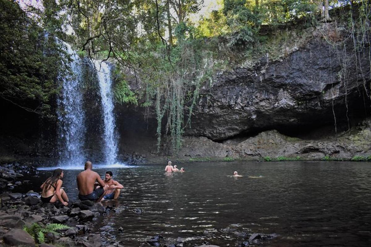 a group of people in the water near a waterfall