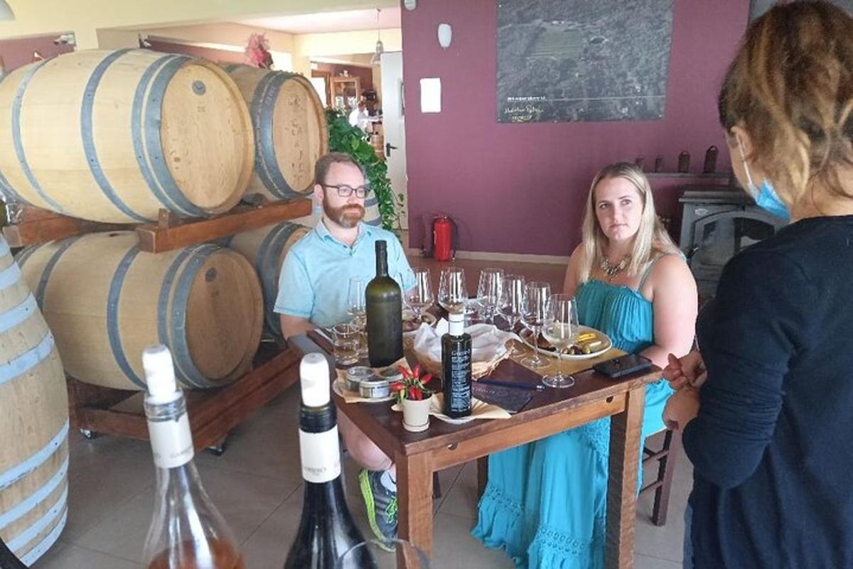 un uomo e una donna seduti a un tavolo con bottiglie di vino
