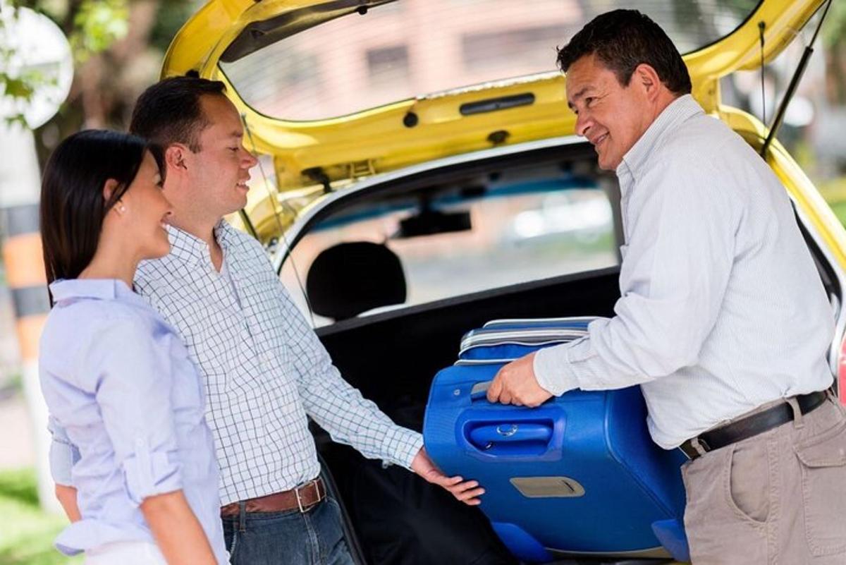 two men and a woman holding a suitcase in the trunk of a car