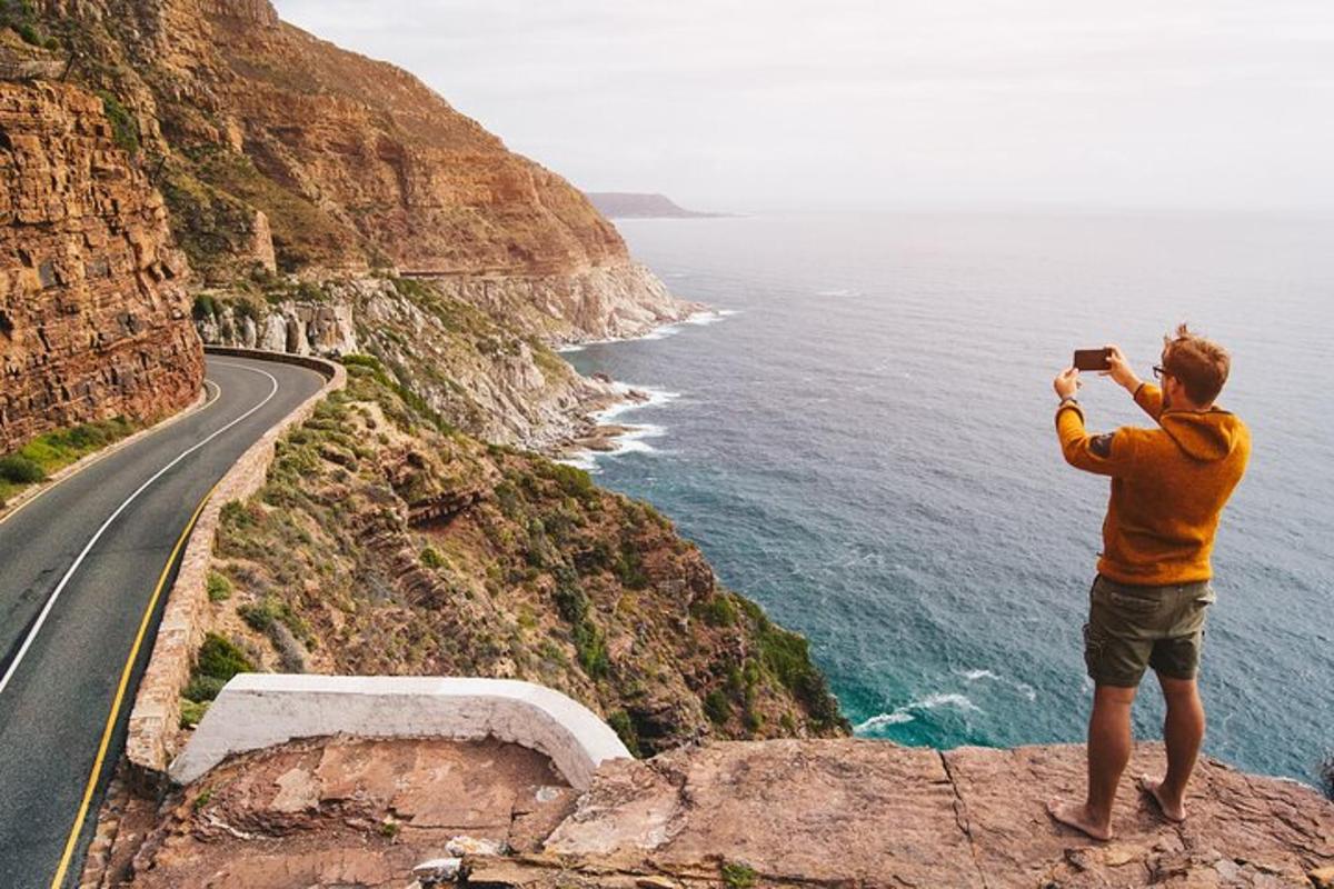 a man taking a picture of the ocean and a road