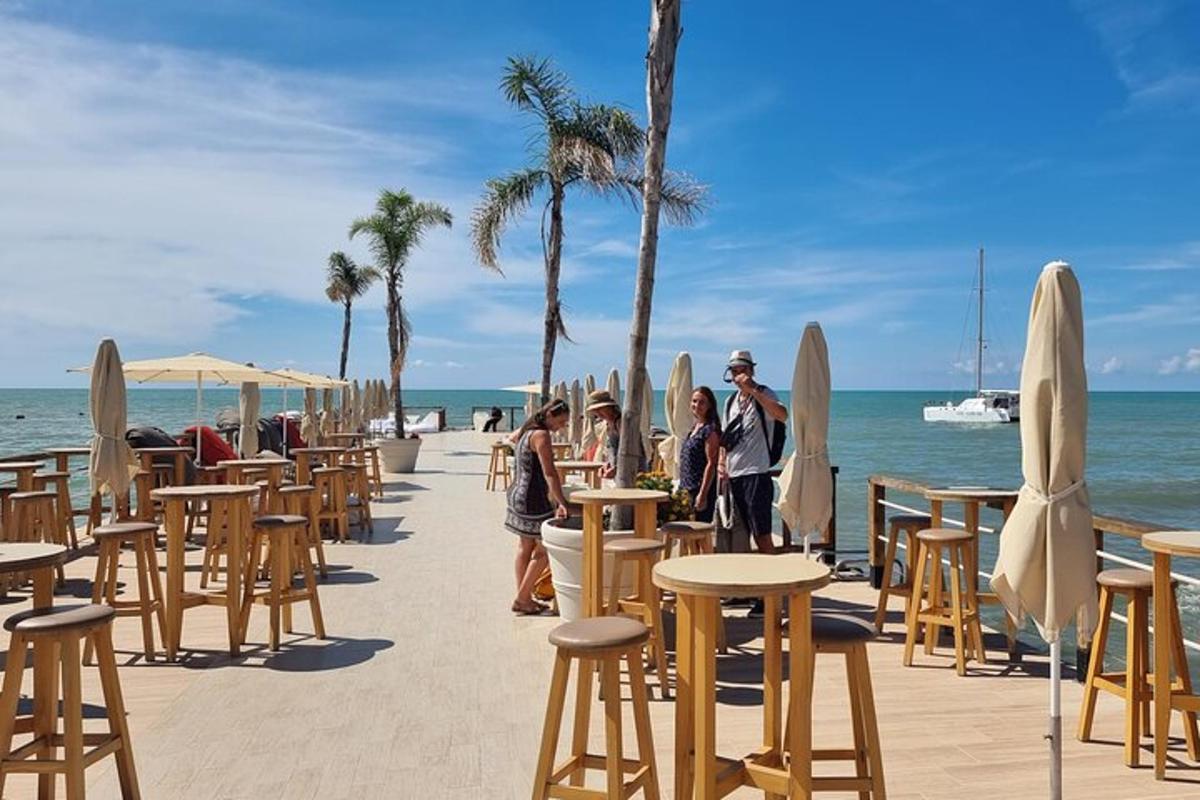 skupina ljudi, ki stojijo na plaži z mizami in stoli