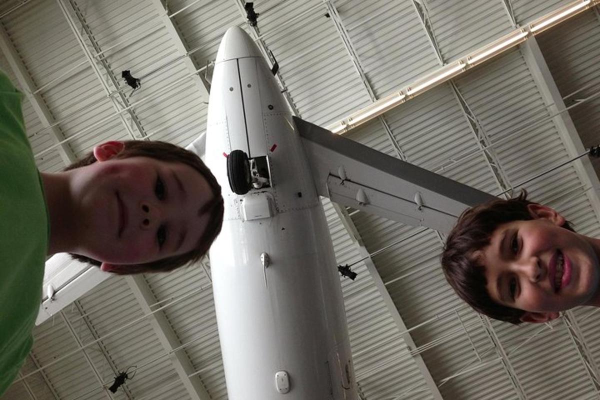 Dos hombres están de pie junto a un cohete en un hangar.