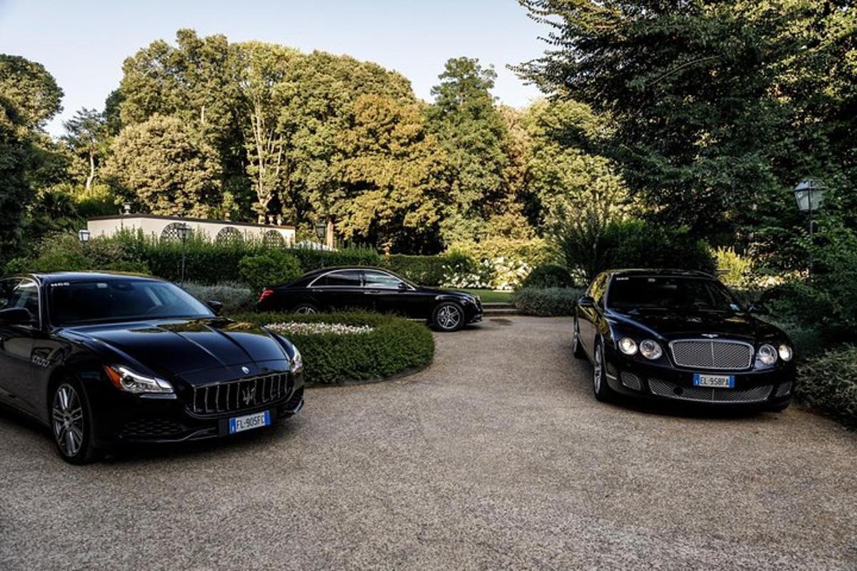 dvě luxusní černá auta zaparkovaná na příjezdové cestě