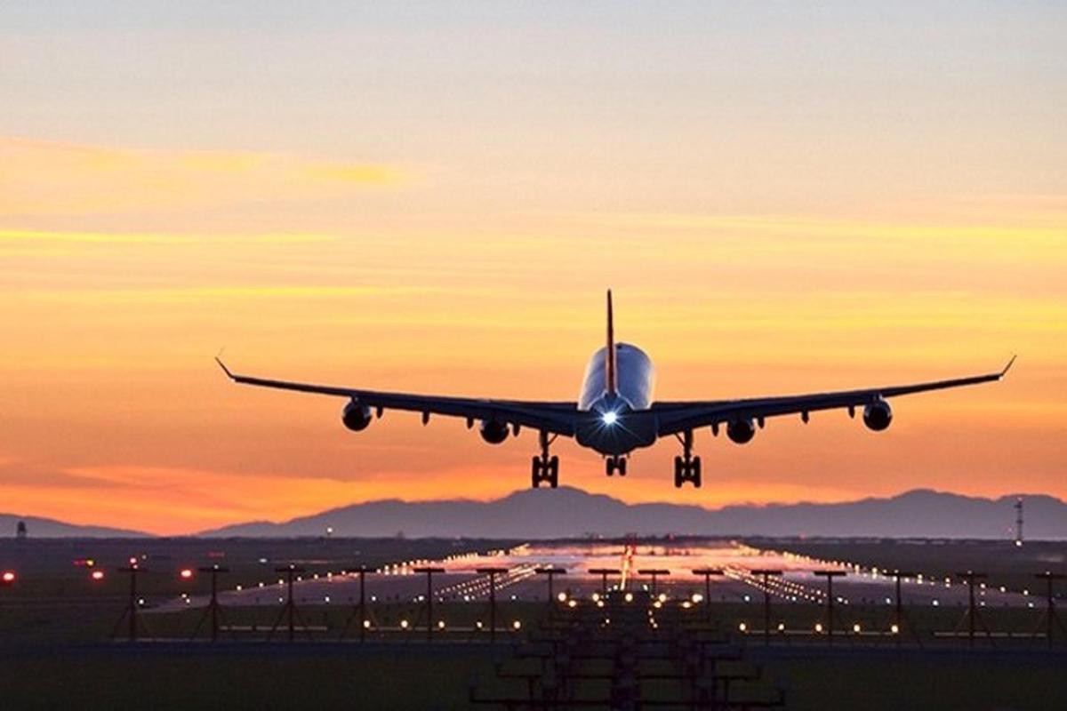 an airplane taking off from an airport runway at sunset