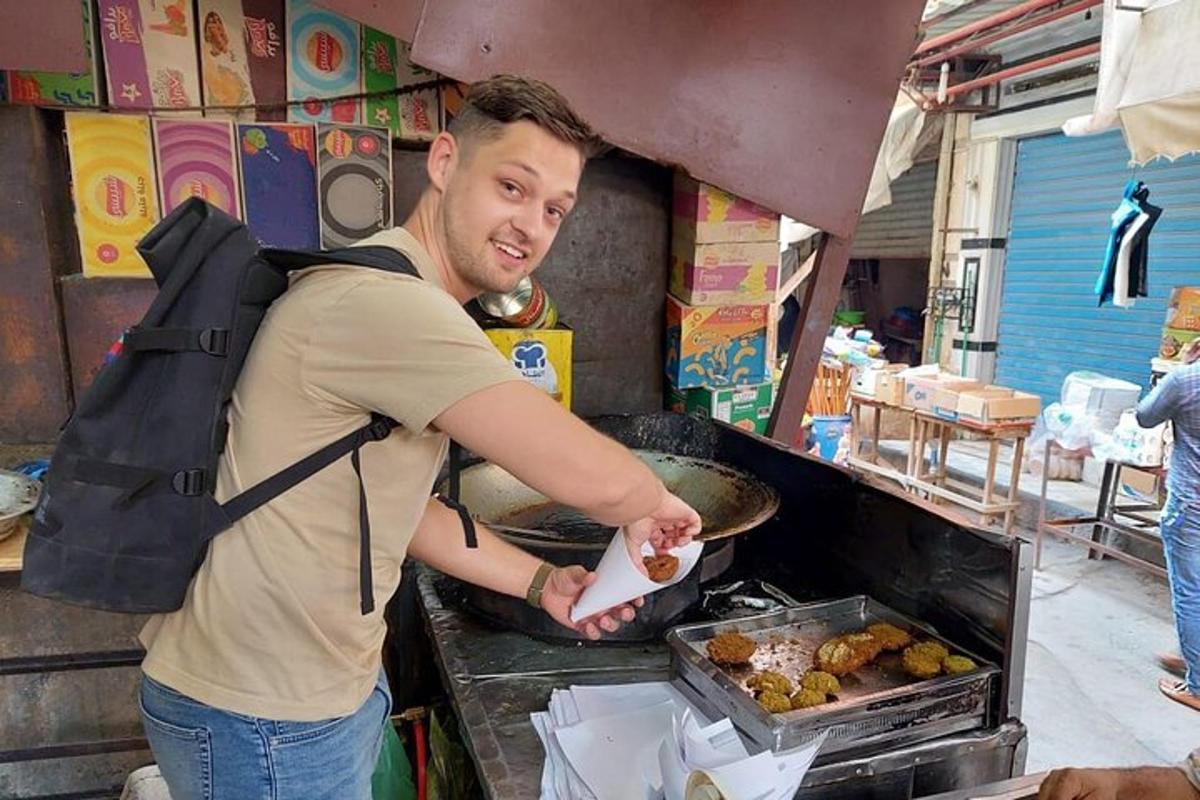 muž s batohem připravující jídlo na grilu