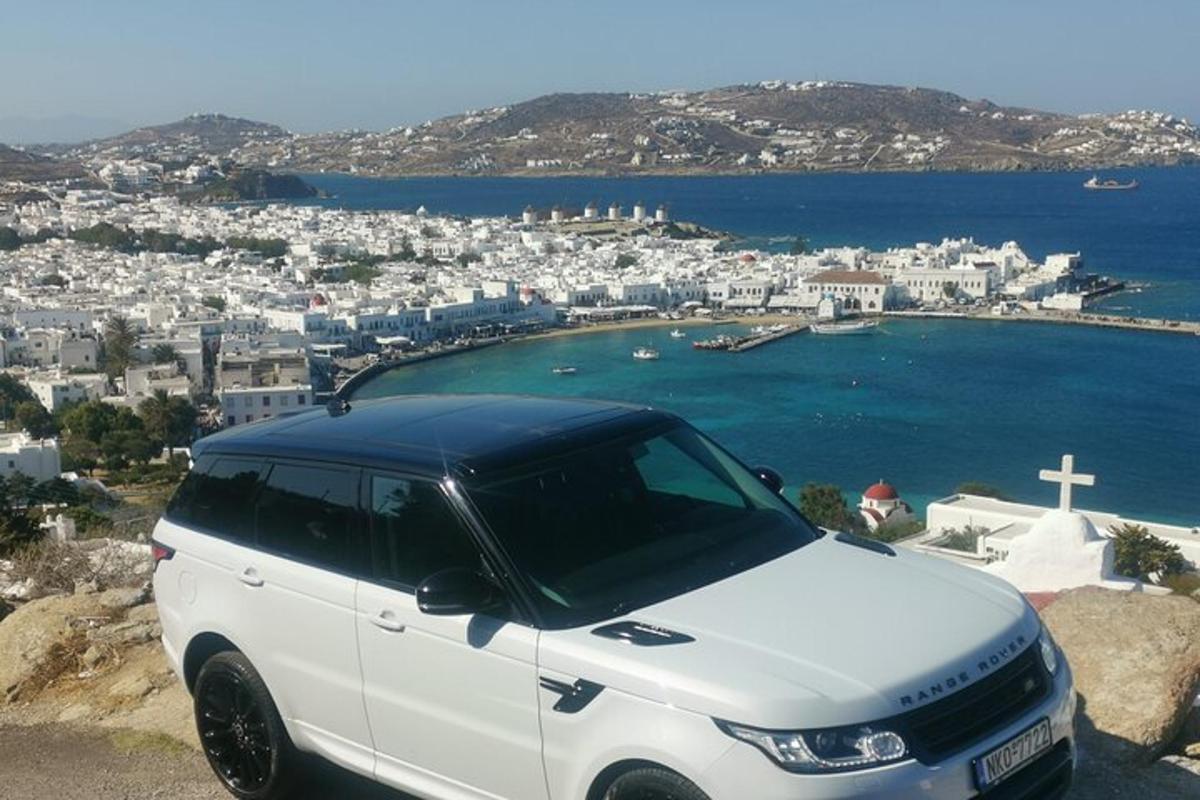 Ένα άσπρο αυτοκίνητο παρκαρισμένο στην κορυφή ενός λόφου με έναν σταυρό