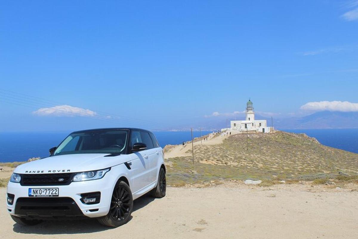 a white car parked in front of a lighthouse