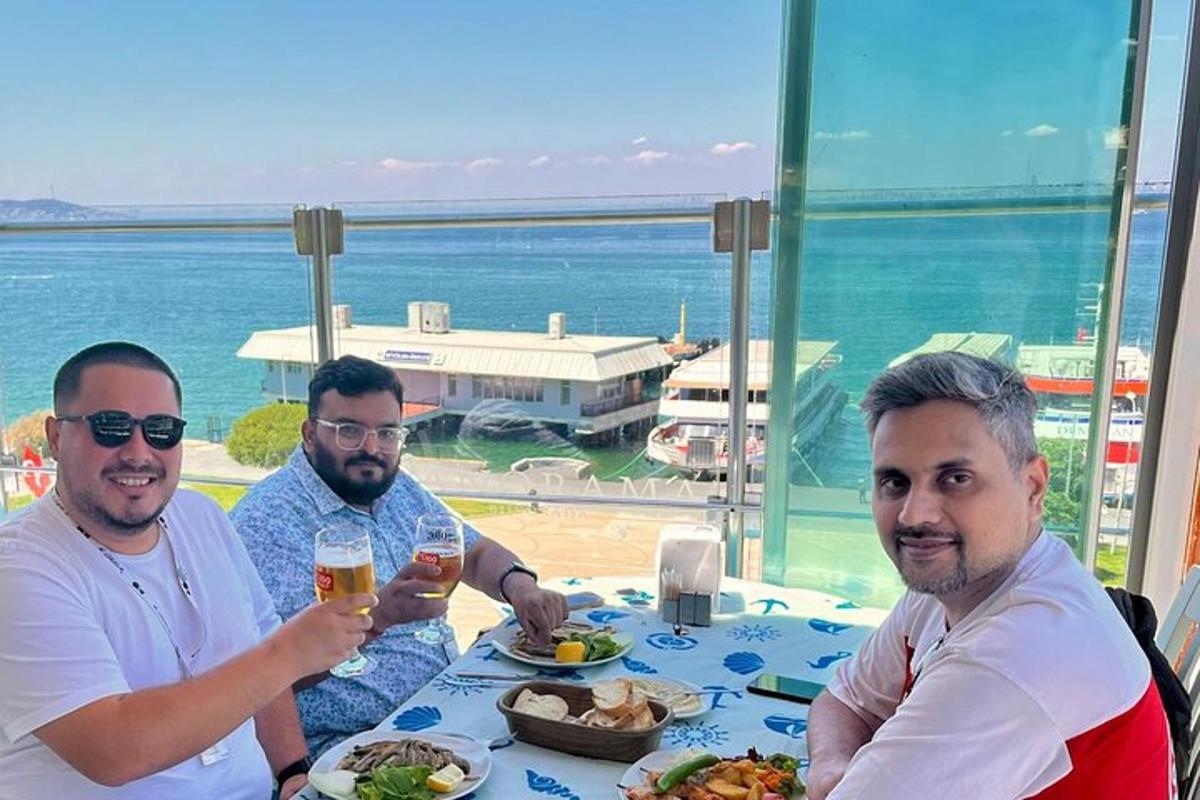 Tres hombres sentados en una mesa con comida y bebidas.