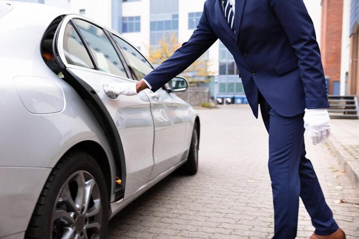 ülikonnas mees seisab auto kõrval