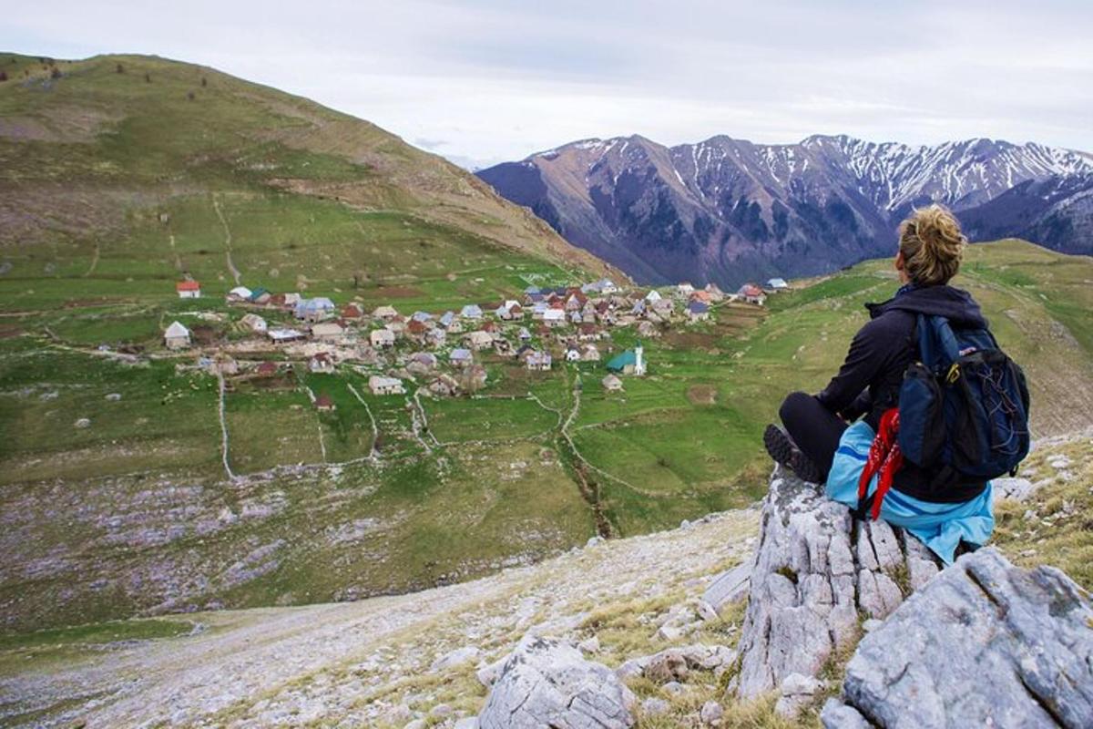 člověk sedící na vrcholu hory a dívající se do údolí